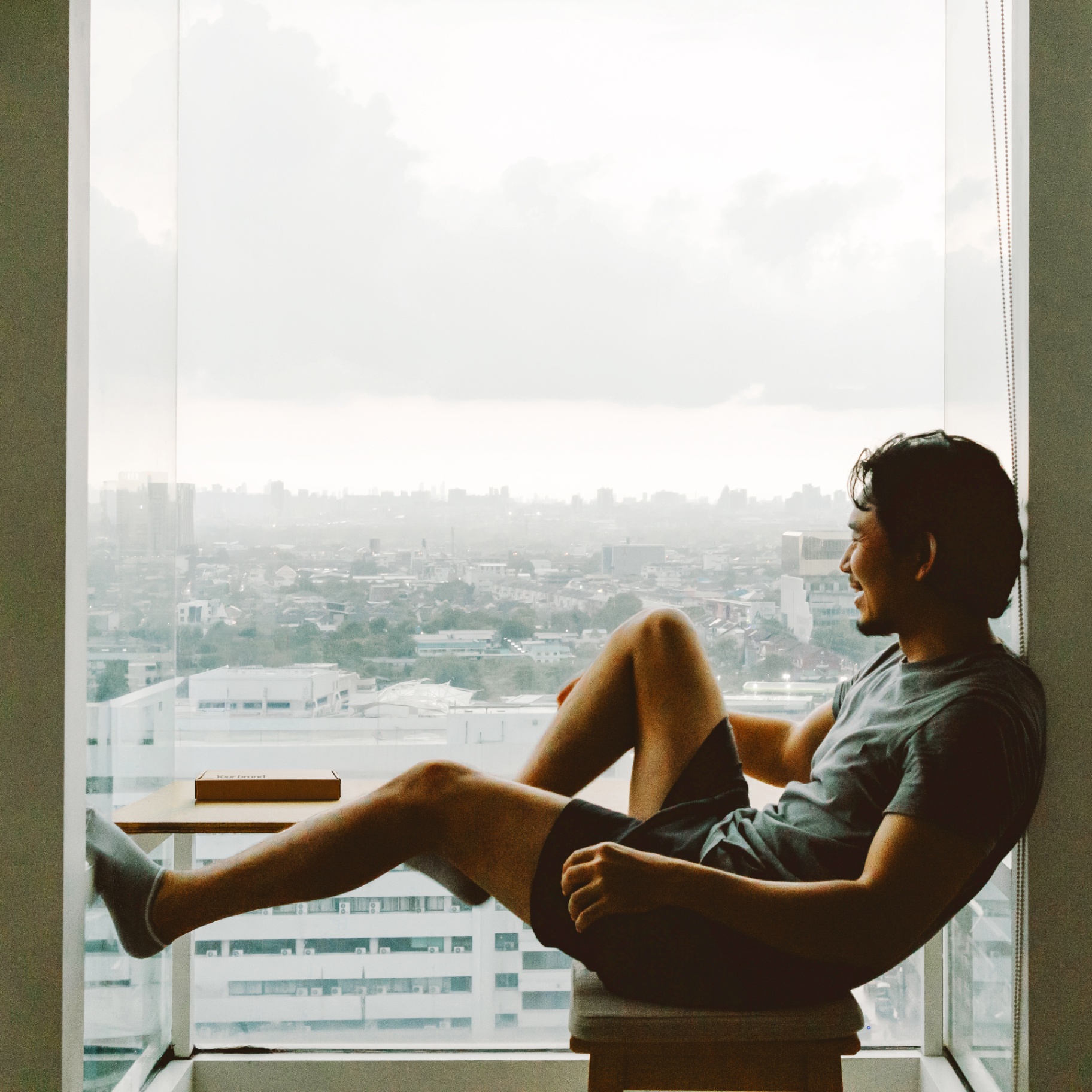 Man relaxing by a window with city view