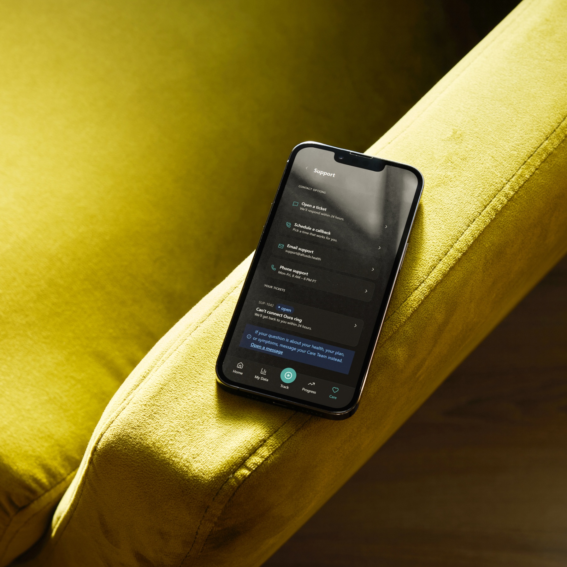 Member support app on a phone resting on a velvet couch